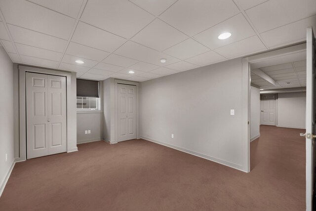 unfurnished bedroom with a paneled ceiling, carpet flooring, and baseboards