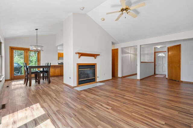 10511 Stoney Point Dr, Delton, MI 49046 - living area featuring a chandelier, a ceiling fan, high vaulted ceiling, light wood-type flooring, and a fireplace with flush hearth