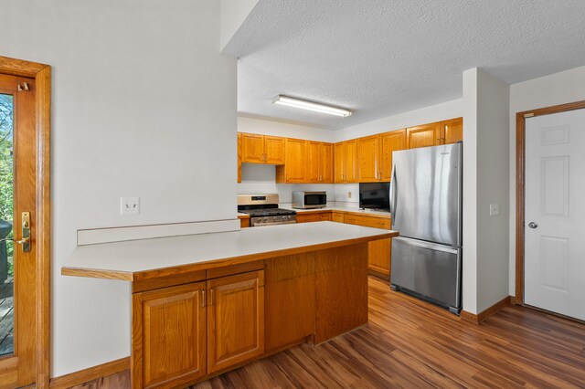 10511 Stoney Point Dr, Delton, MI 49046 - kitchen with stainless steel appliances, a peninsula, dark wood-style floors, light countertops, and baseboards