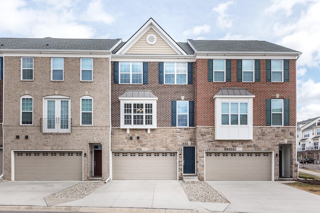 view of property featuring a garage, driveway, stone siding, and brick siding