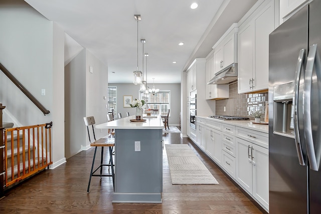 kitchen featuring stainless steel appliances, tasteful backsplash, baseboards, white cabinetry, and under cabinet range hood