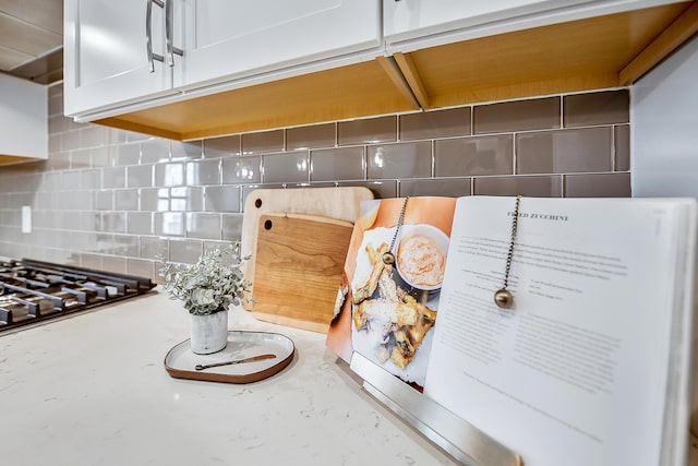 interior details featuring white cabinets, stainless steel gas cooktop, and backsplash