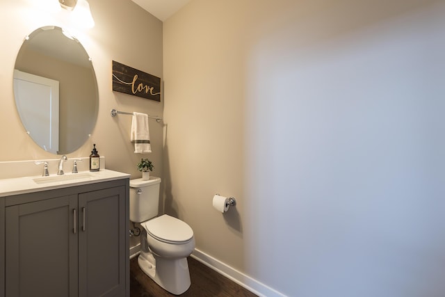 bathroom featuring toilet, vanity, wood finished floors, and baseboards