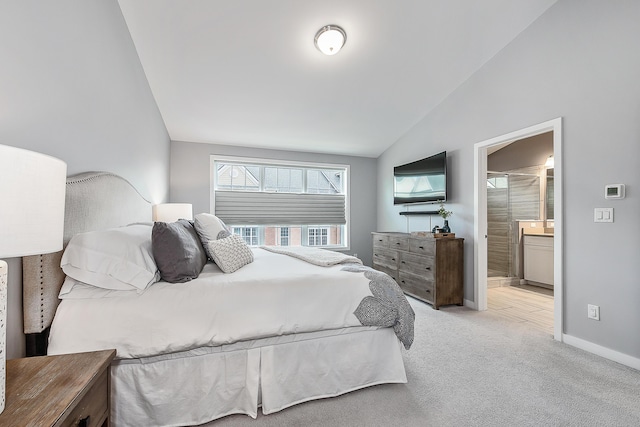 bedroom featuring connected bathroom, lofted ceiling, carpet floors, and baseboards