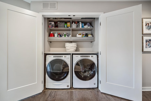 clothes washing area featuring visible vents, washer and clothes dryer, laundry area, and dark wood-style flooring