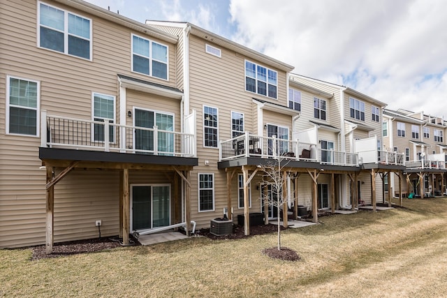 back of house with a lawn, central AC unit, and a residential view