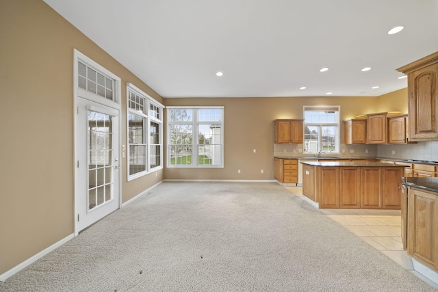 kitchen featuring decorative backsplash, light colored carpet, baseboards, and a kitchen island