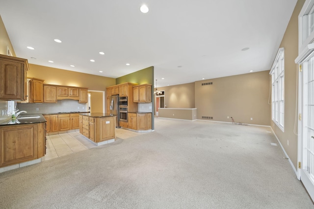 kitchen with visible vents, a center island, open floor plan, dark countertops, and light colored carpet