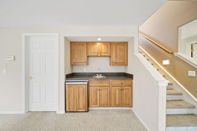 kitchen with a sink, dark countertops, light colored carpet, and dishwasher