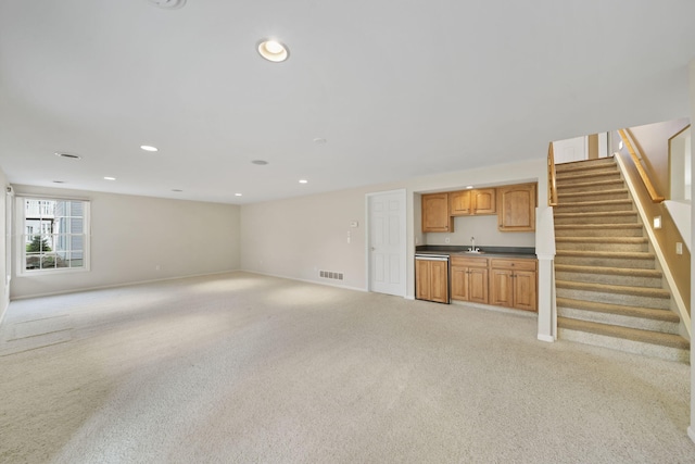 unfurnished living room with indoor wet bar, baseboards, stairs, visible vents, and light colored carpet