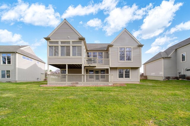rear view of house featuring central AC unit, a sunroom, and a lawn