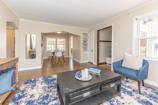 living area featuring baseboards, ornamental molding, and wood finished floors