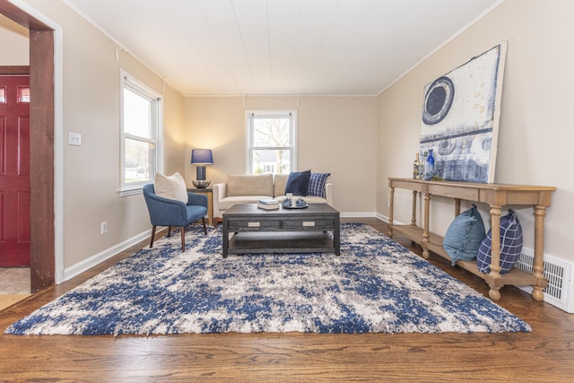 living room with baseboards, crown molding, and wood finished floors