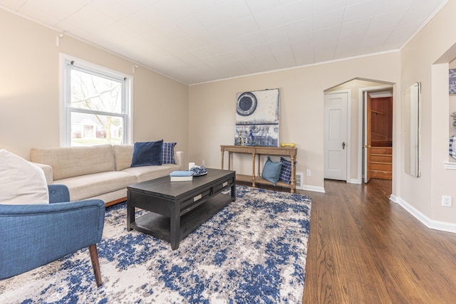 living area with crown molding, wood finished floors, baseboards, and arched walkways