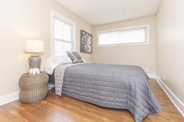 bedroom featuring crown molding, wood finished floors, and baseboards