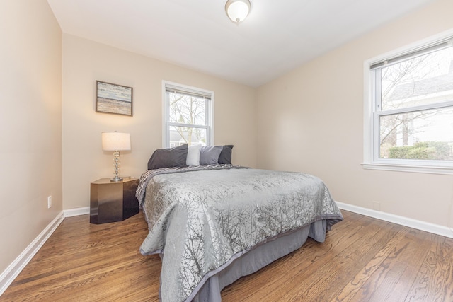 bedroom with baseboards, multiple windows, and wood finished floors