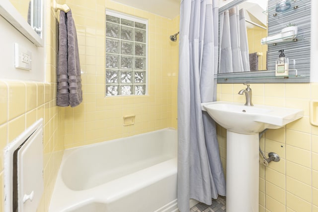 bathroom with shower / bath combo and tile walls