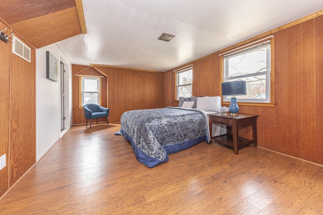 bedroom with wood finished floors, wood walls, and visible vents