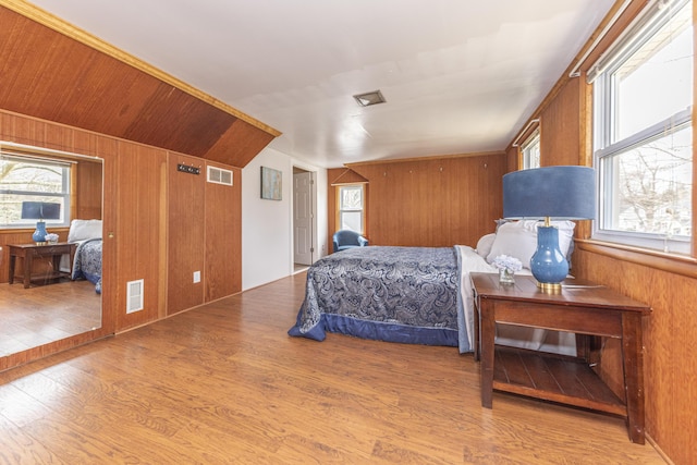 bedroom featuring wood finished floors, wood walls, and visible vents