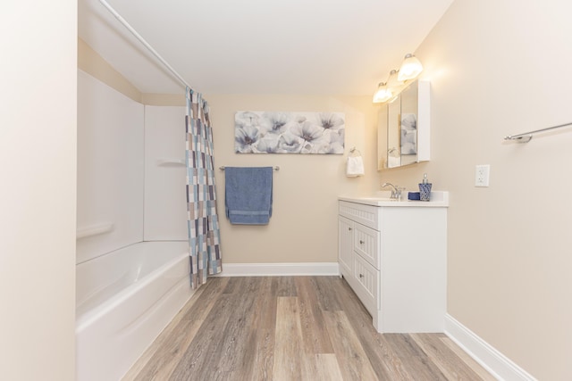 bathroom with shower / tub combo, vanity, baseboards, and wood finished floors