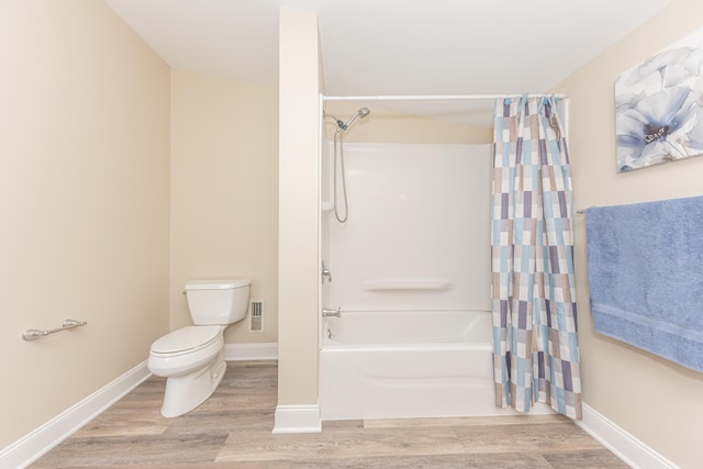 bathroom with shower / bath combo, toilet, wood finished floors, and baseboards