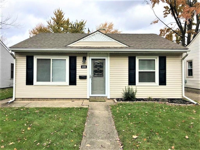 bungalow featuring a front yard and a shingled roof