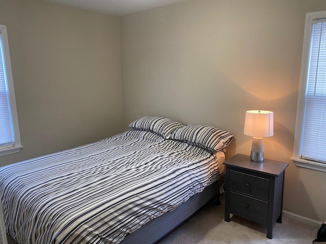 bedroom with light carpet, baseboards, and multiple windows
