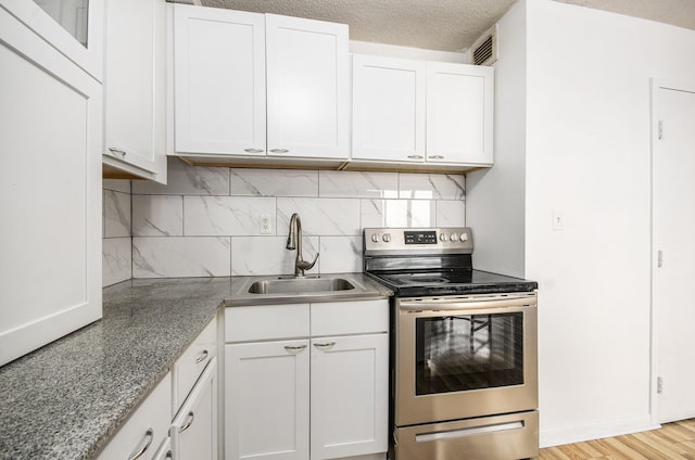 8900 E Jefferson Ave Unit 1109, Detroit, MI 48214 - kitchen with electric range, white cabinetry, visible vents, a sink, and backsplash
