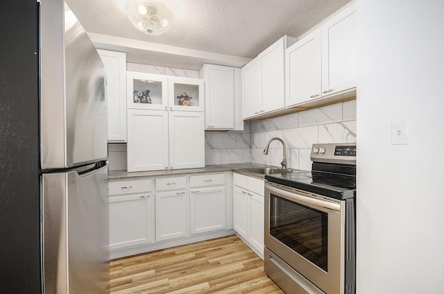 8900 E Jefferson Ave Unit 1109, Detroit, MI 48214 - kitchen featuring a textured ceiling, white cabinets, a sink, stainless steel appliances, and light wood finished floors