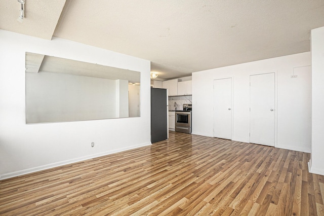 8900 E Jefferson Ave Unit 1109, Detroit, MI 48214 - unfurnished living room with wood finished floors, a sink, and baseboards
