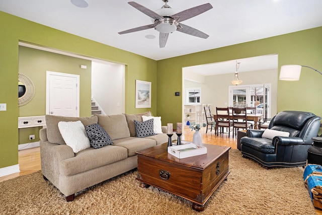living area with a ceiling fan, wood finished floors, and stairs