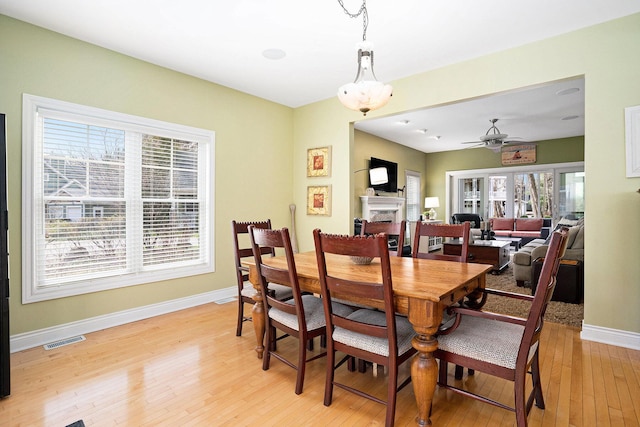 dining space with visible vents, baseboards, ceiling fan, light wood-type flooring, and a fireplace