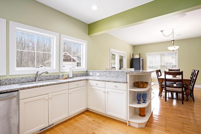 kitchen featuring stainless steel dishwasher, light wood-style flooring, open shelves, visible vents, and a sink