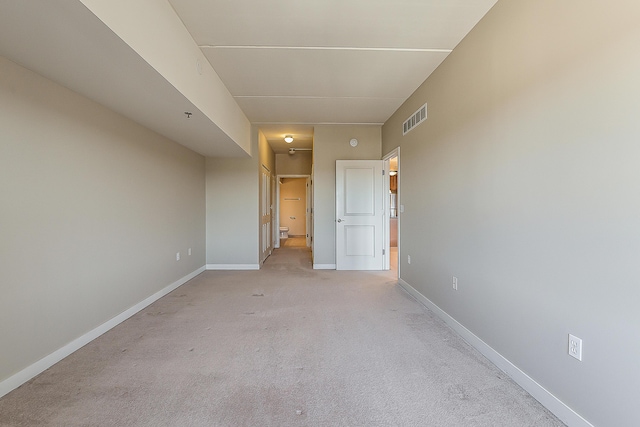 unfurnished room featuring light carpet, visible vents, and baseboards