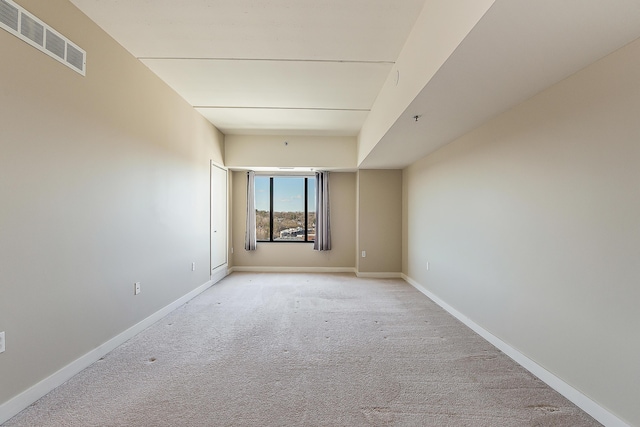 spare room featuring baseboards, visible vents, and light colored carpet