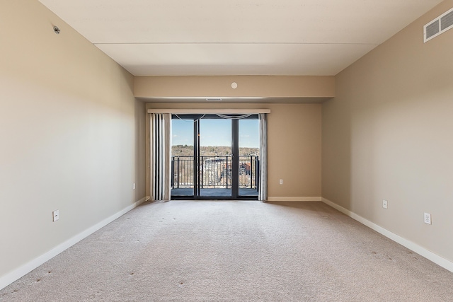 unfurnished room with carpet, visible vents, and baseboards