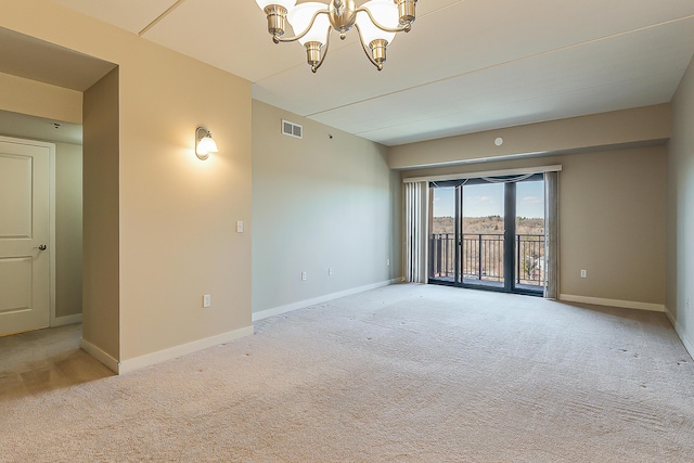 spare room featuring baseboards, visible vents, light colored carpet, and an inviting chandelier