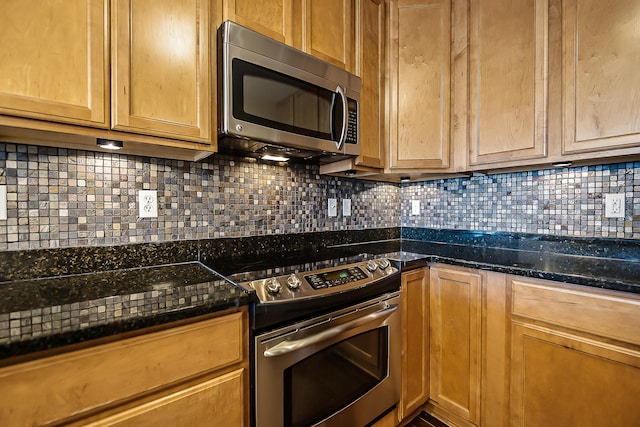 kitchen featuring stainless steel appliances, decorative backsplash, and dark stone countertops