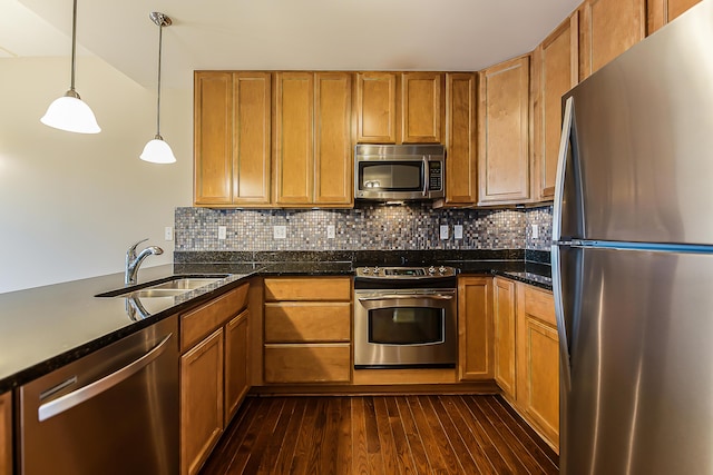 kitchen with stainless steel appliances, a sink, dark wood finished floors, and tasteful backsplash