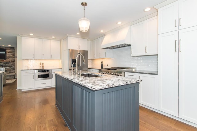940 E Eagle Lake Dr, Kalamazoo, MI 49009 - kitchen with custom exhaust hood, a sink, stainless steel appliances, wood finished floors, and recessed lighting