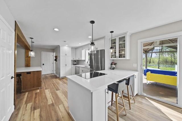 5427 Vrooman Rd, Jackson, MI 49201 - kitchen with glass insert cabinets, light wood-style floors, appliances with stainless steel finishes, white cabinets, and a peninsula