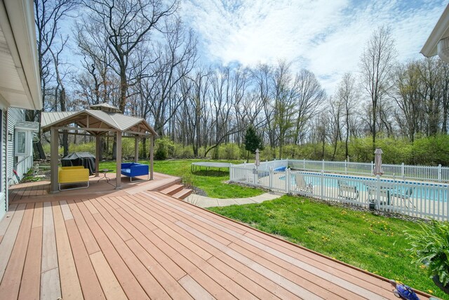 5427 Vrooman Rd, Jackson, MI 49201 - deck featuring a trampoline, a fenced in pool, a gazebo, fence, and a yard