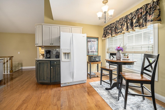 500 Mckinley, Three Rivers, MI 49093 - kitchen featuring white fridge with ice dispenser, light wood-style flooring, tasteful backsplash, baseboards, and a notable chandelier