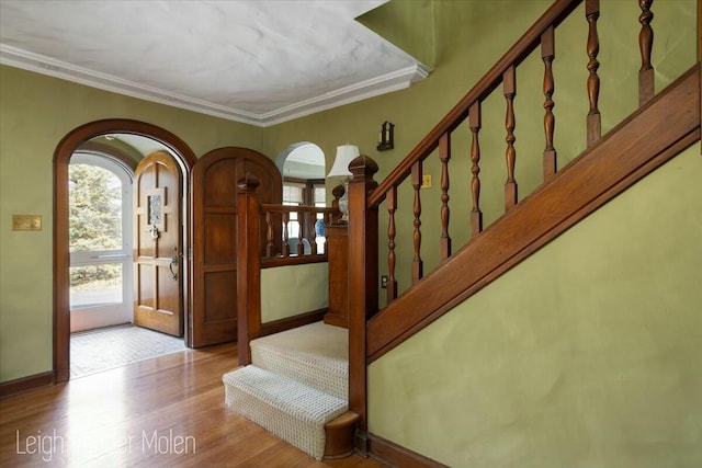 3020 Fulton St SE, Grand Rapids, MI 49506 - foyer featuring arched walkways, wood finished floors, stairs, ornamental molding, and baseboards