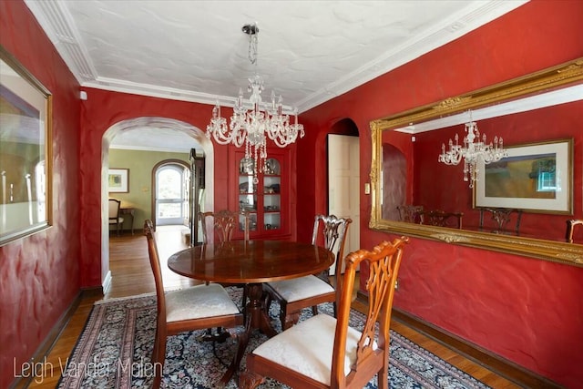 3020 Fulton St SE, Grand Rapids, MI 49506 - dining area with arched walkways, a chandelier, wood finished floors, baseboards, and ornamental molding