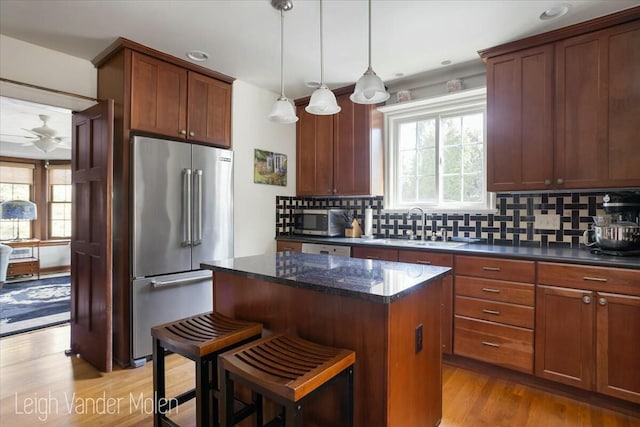 3020 Fulton St SE, Grand Rapids, MI 49506 - kitchen featuring appliances with stainless steel finishes, a sink, tasteful backsplash, a kitchen island, and light wood-type flooring