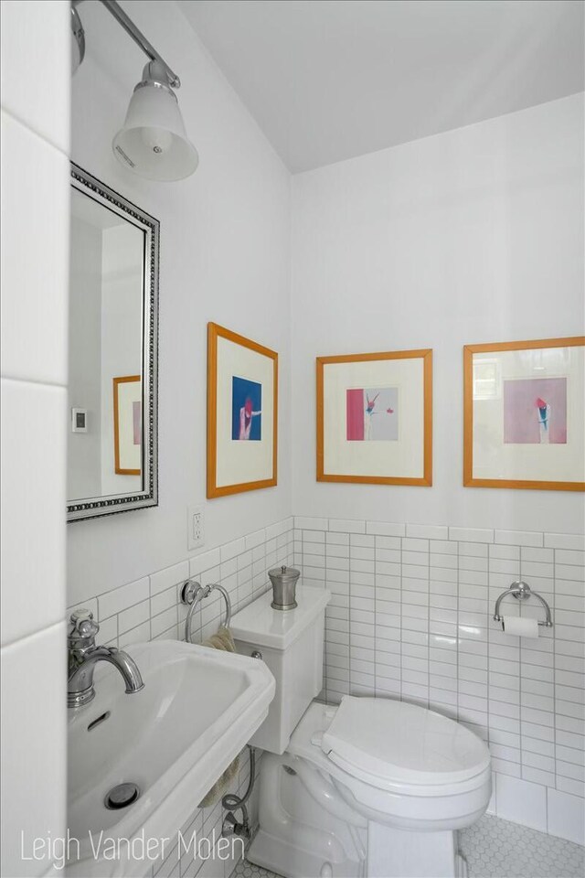 3020 Fulton St SE, Grand Rapids, MI 49506 - half bath featuring tile walls, a sink, toilet, and a wainscoted wall