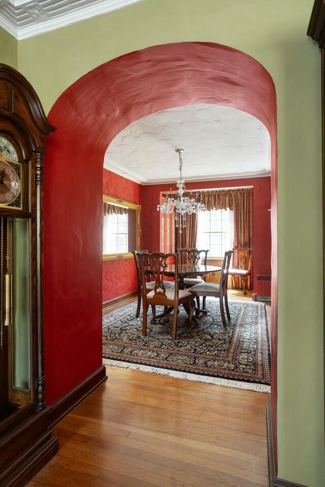 3020 Fulton St SE, Grand Rapids, MI 49506 - dining space featuring a chandelier, arched walkways, hardwood / wood-style floors, baseboards, and ornamental molding