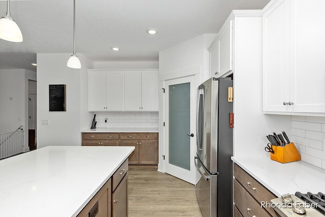 kitchen featuring white cabinets, freestanding refrigerator, and light wood-style floors