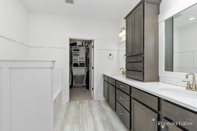 bathroom featuring a sink, visible vents, a walk in closet, and double vanity